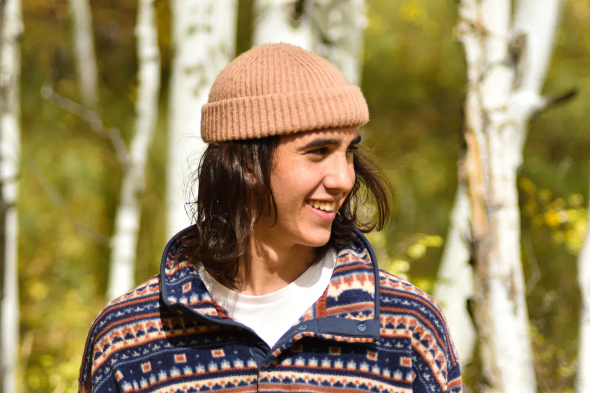 Smiling young man in a beanie and patterned fleece among aspens